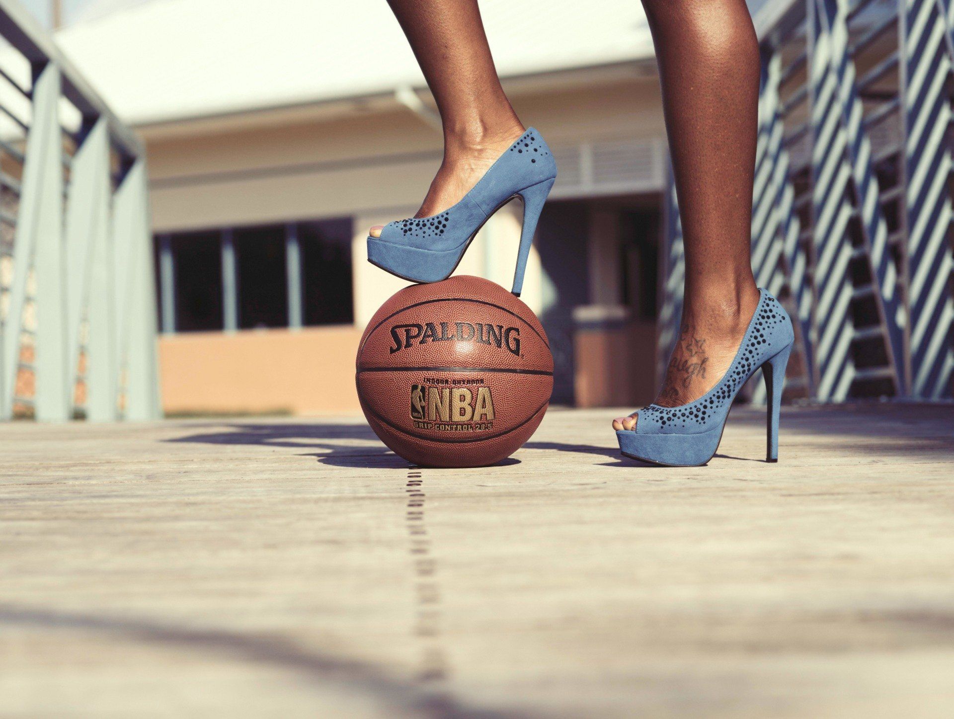 A woman wearing high heels is standing on a basketball.