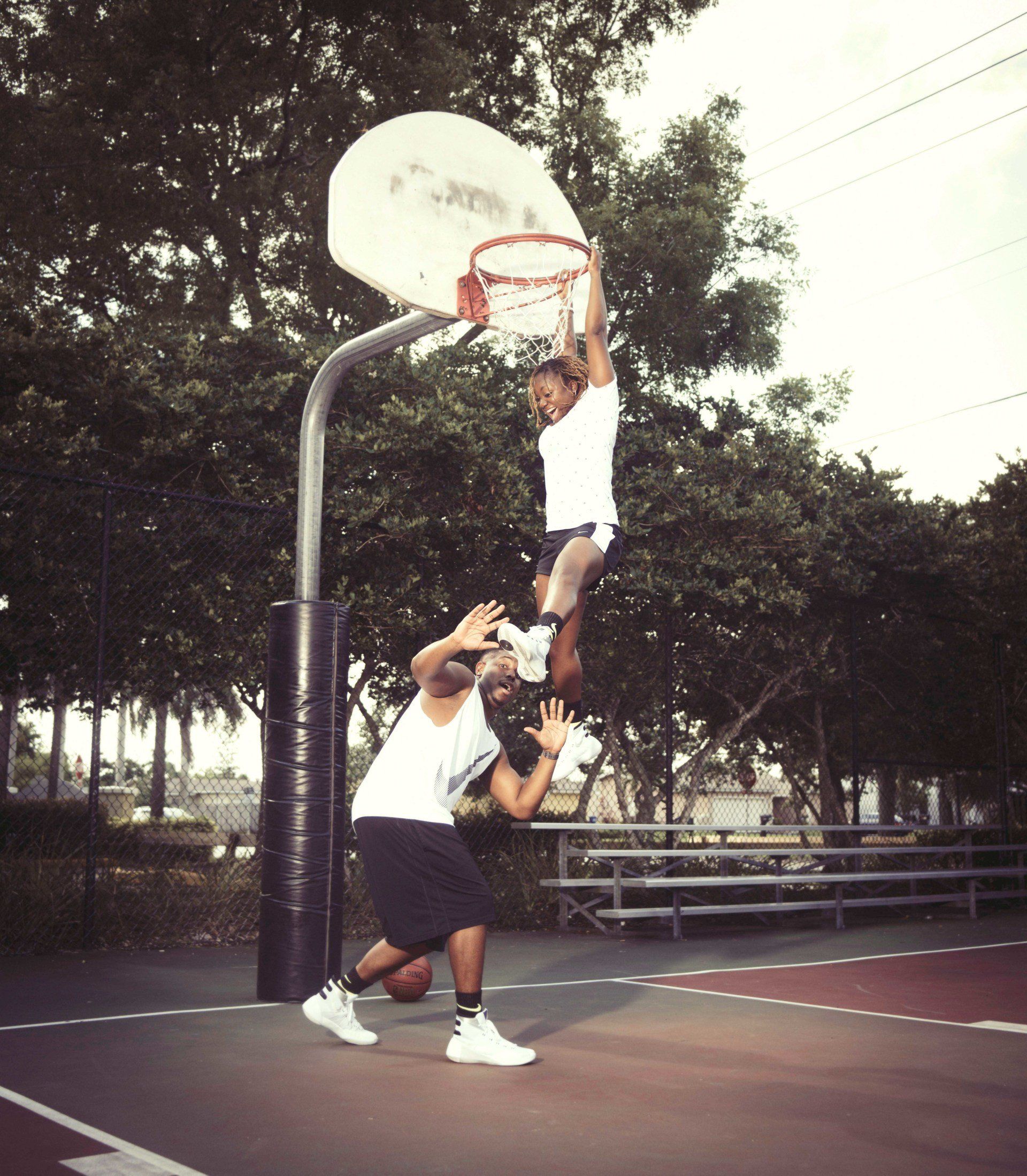 A man and a woman are playing basketball in a park