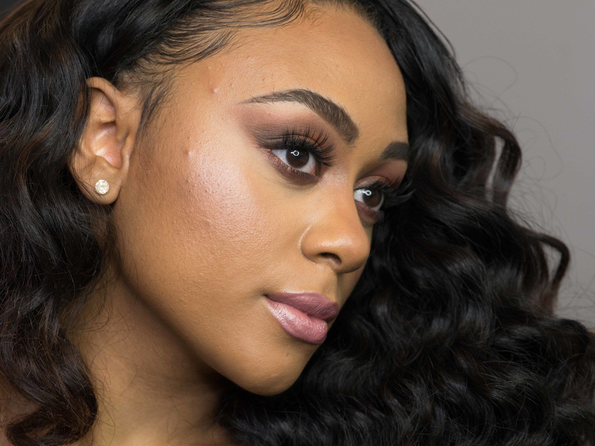 A close up of a woman 's face with long hair and earrings.