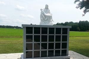 There is a statue of jesus holding a baby in a cemetery.
