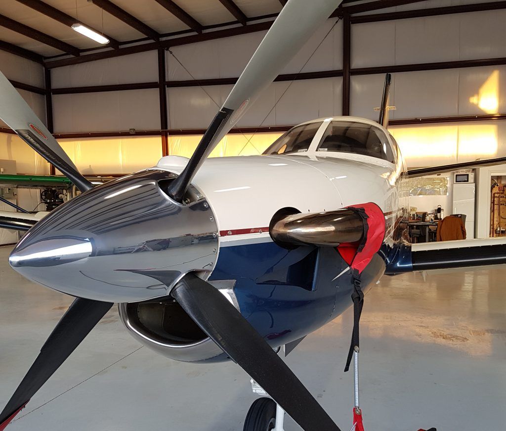 Turboprop airplane with white and blue fuselage, parked in a hangar.