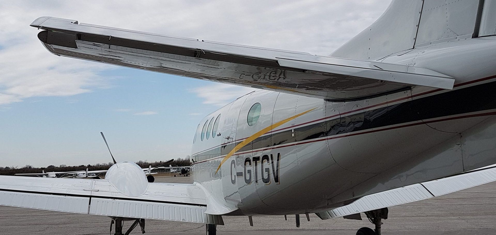 The rear of a white airplane with black stripes and the letters C-GTGV. Blue sky is visible.