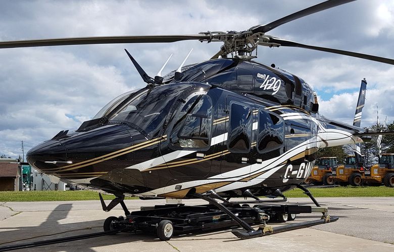 Black and gold helicopter on a landing pad, with the registration number