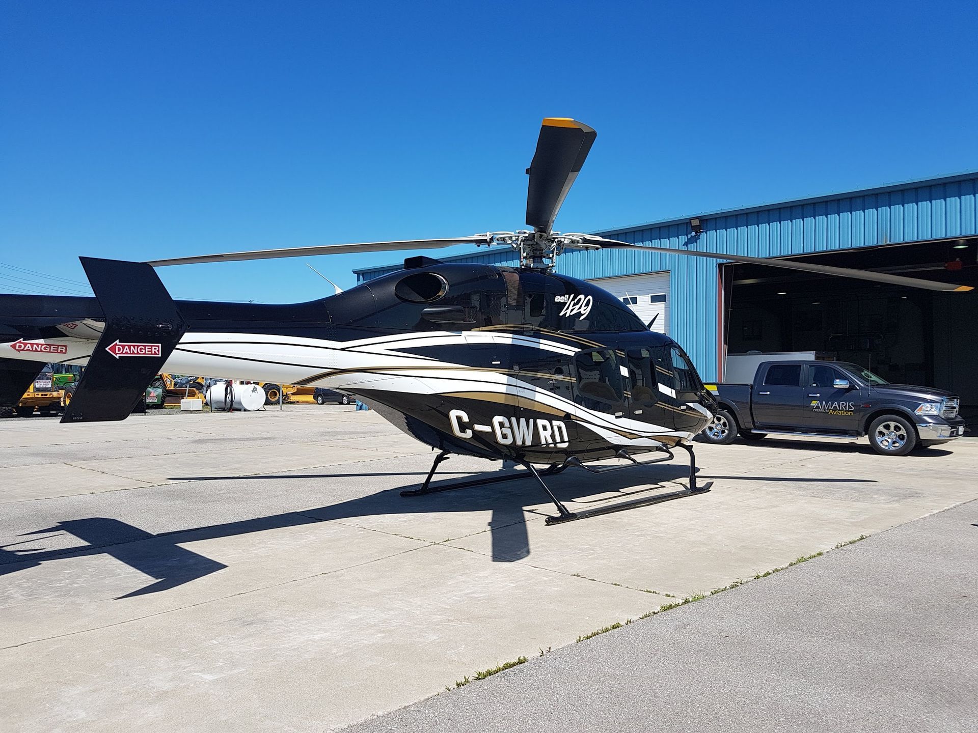 Black and white helicopter on a tarmac, under a clear blue sky. Registration number C-GWRC is visible.