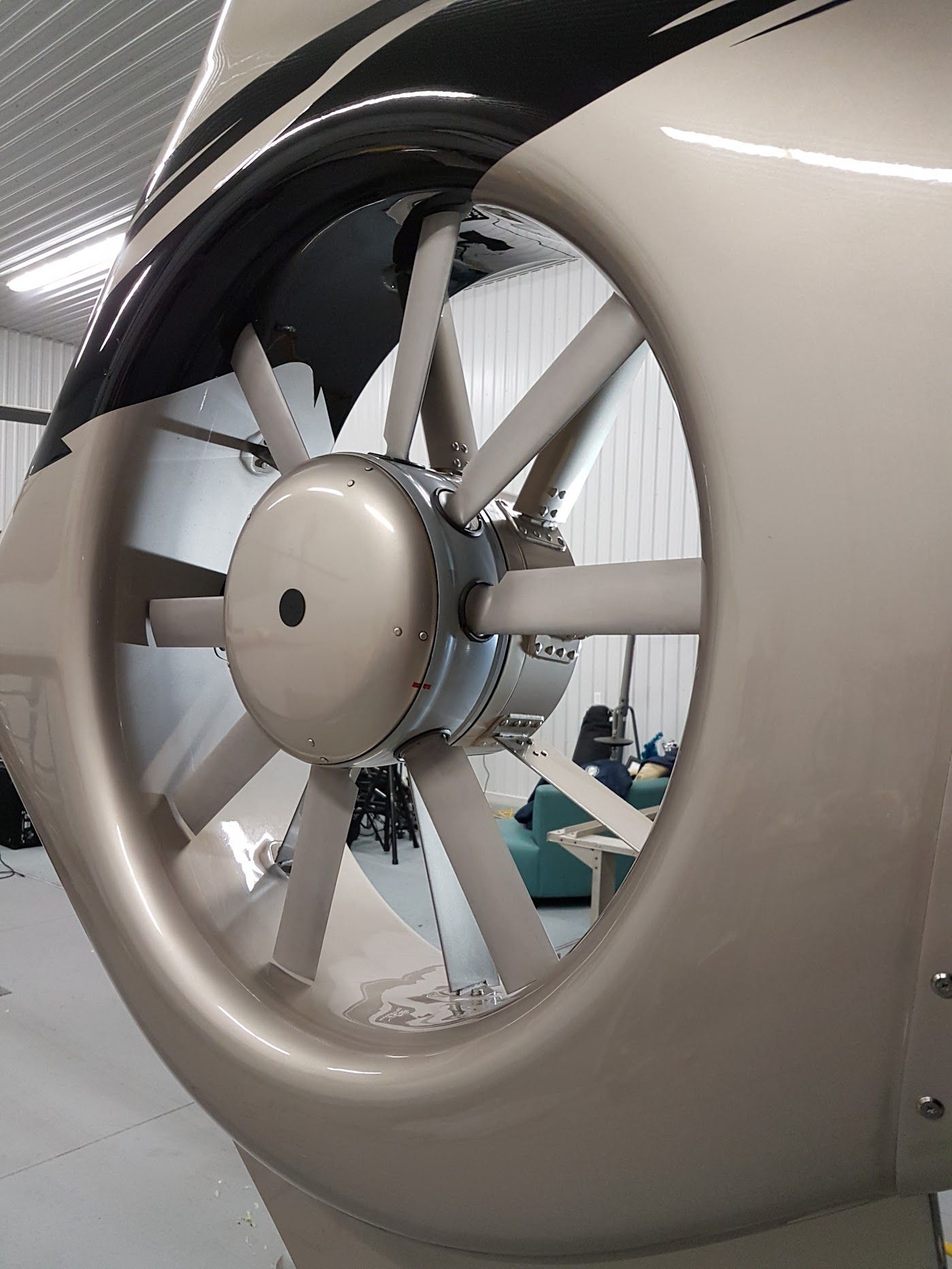 Close-up of a helicopter's tail rotor. Silver fan blades inside a rounded housing. Metallic paint and rivets.