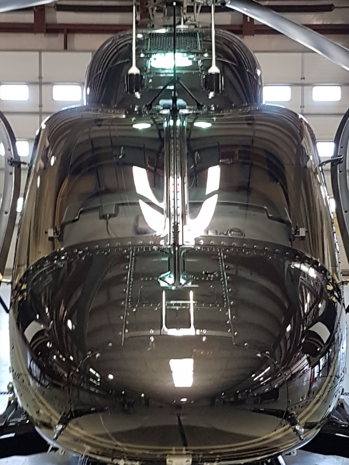 Shiny black helicopter cockpit reflecting the hangar and lights.