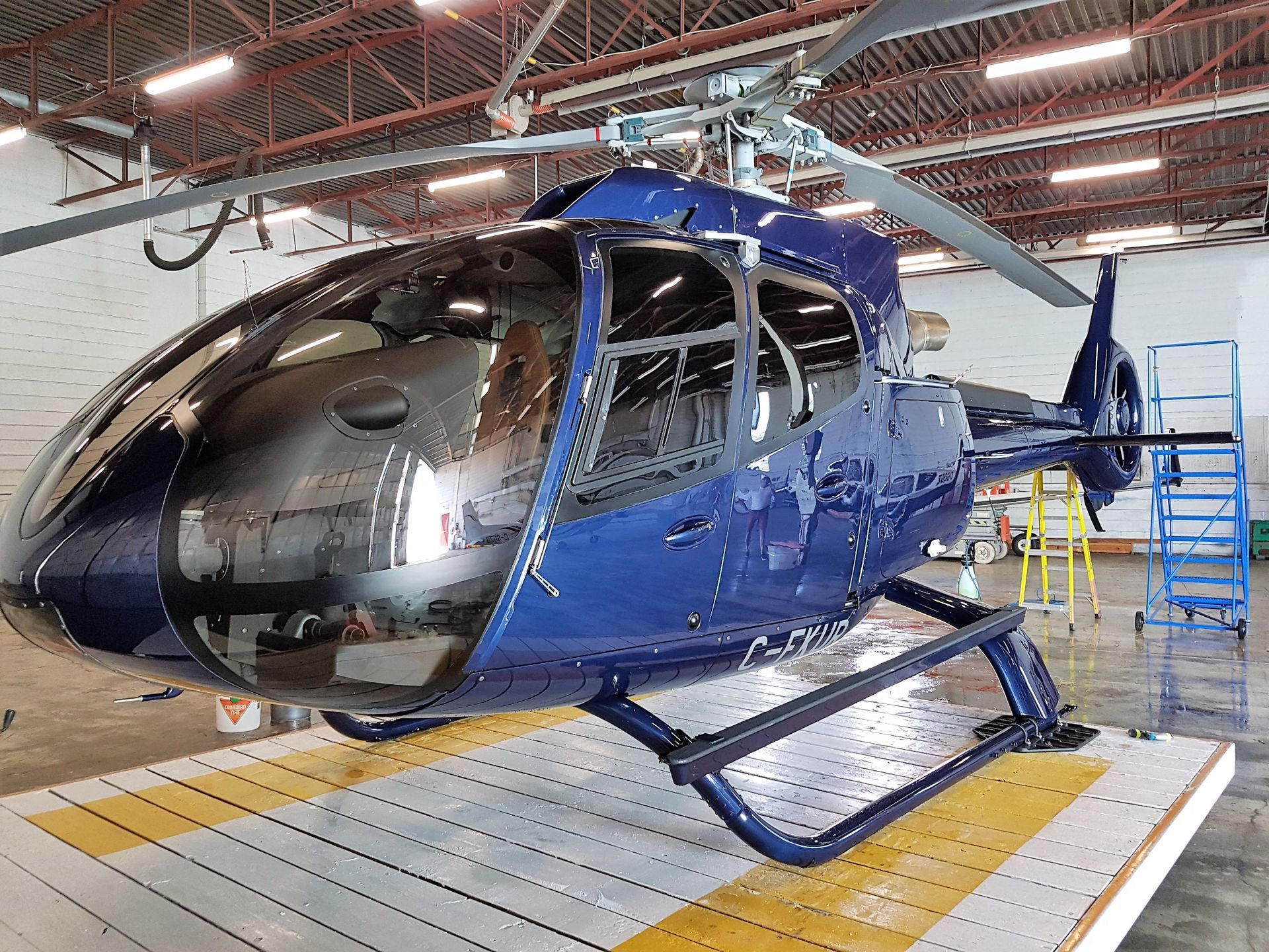 Blue helicopter on a helipad inside a hangar.
