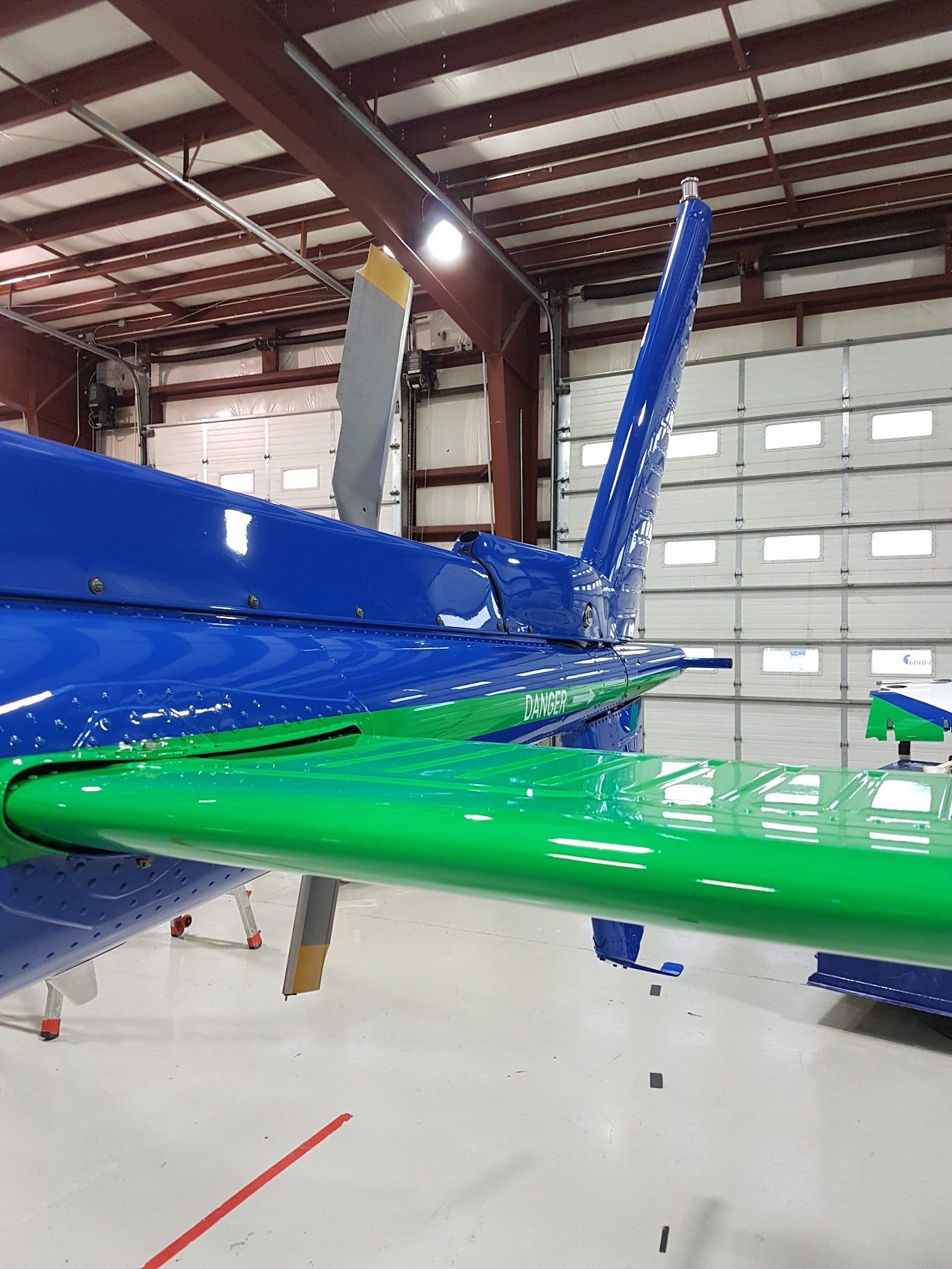 Blue and green airplane tail and wing in a hangar.