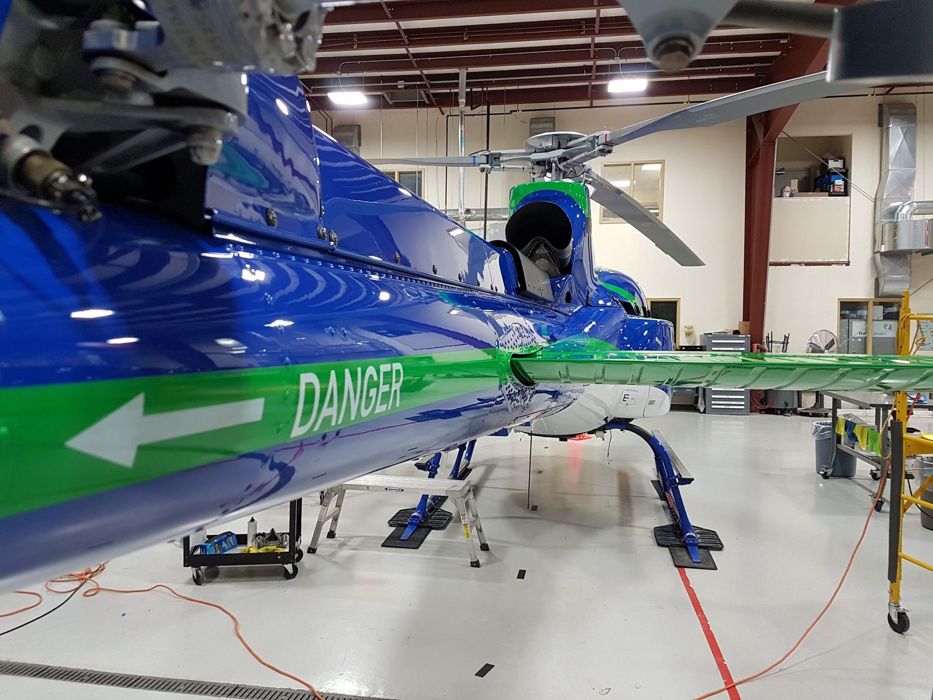 Blue and green helicopter in a hangar with a
