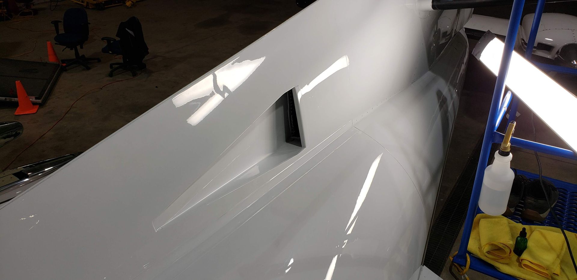 White aircraft wing with a black rectangular opening, possibly an air vent.