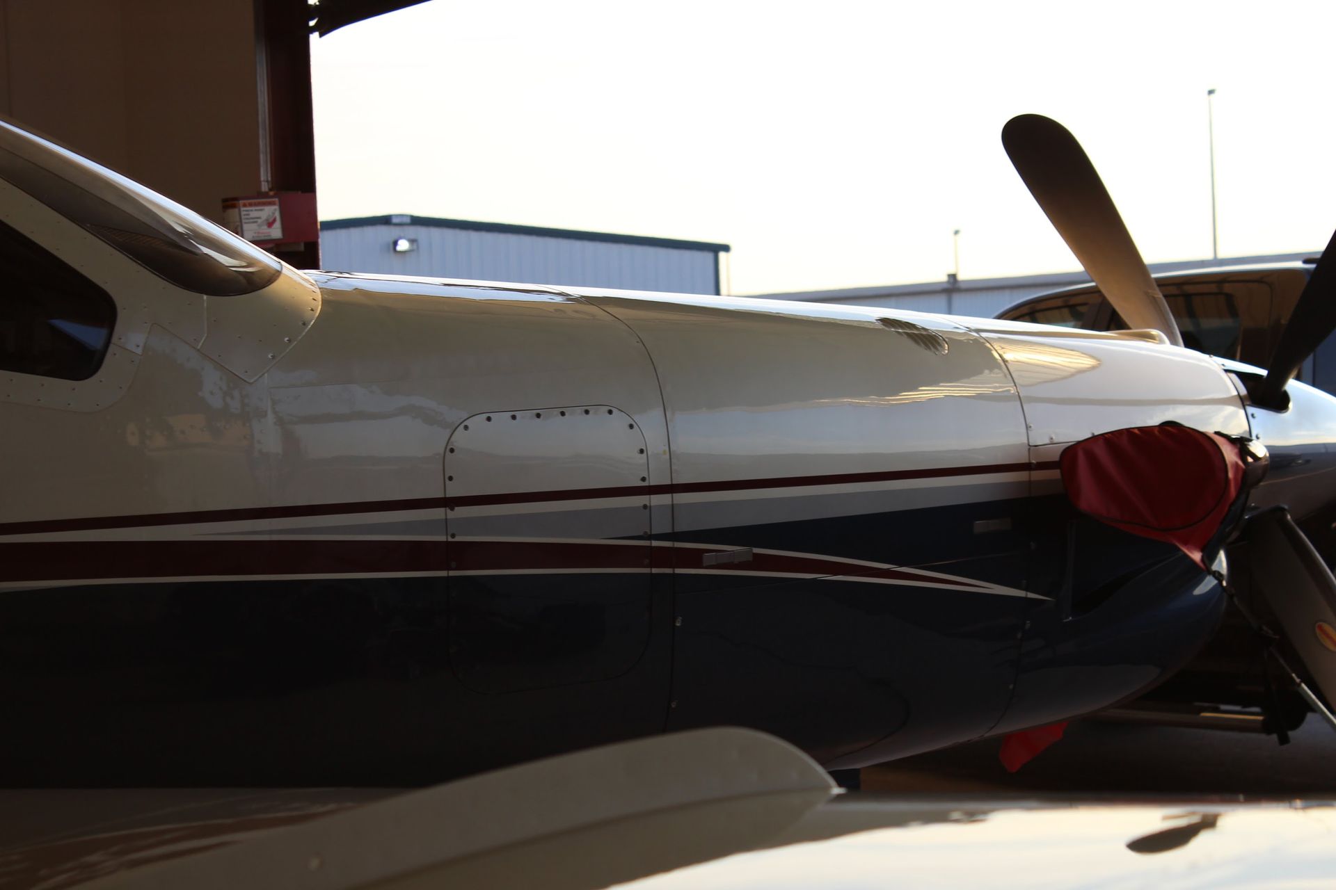 Close-up of a white and blue airplane with a red cover on the engine.