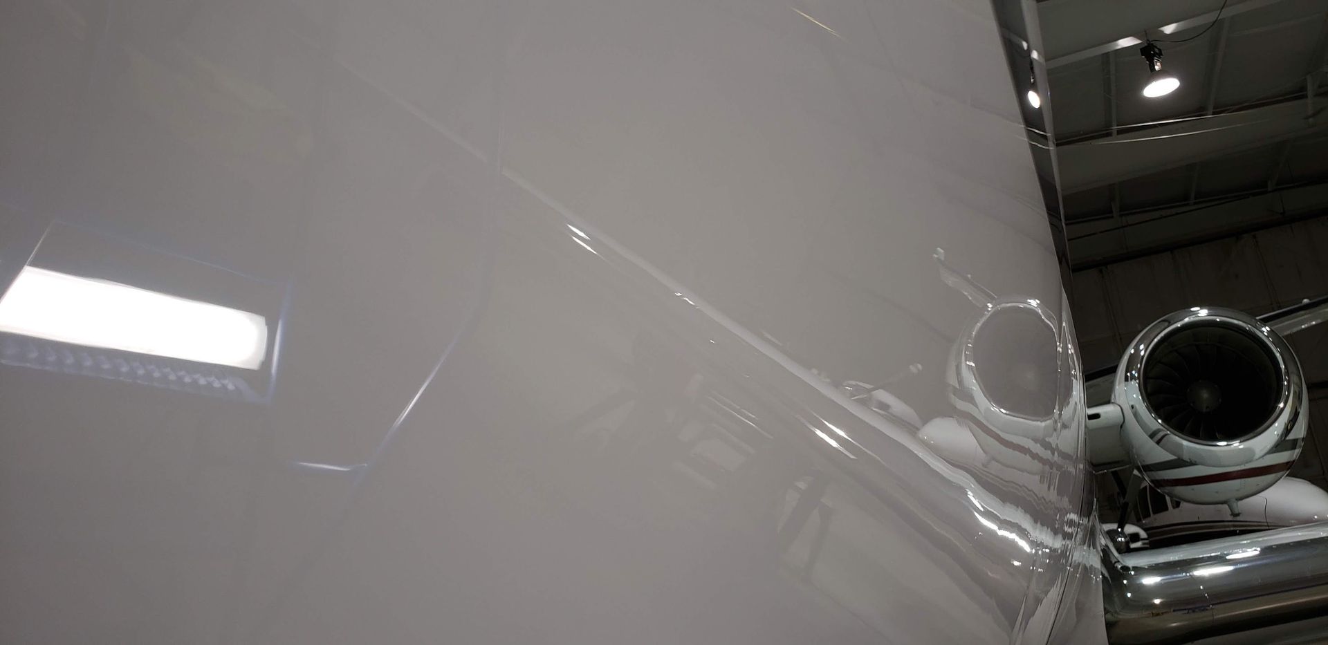 Close-up view of a white airplane fuselage with an engine visible.