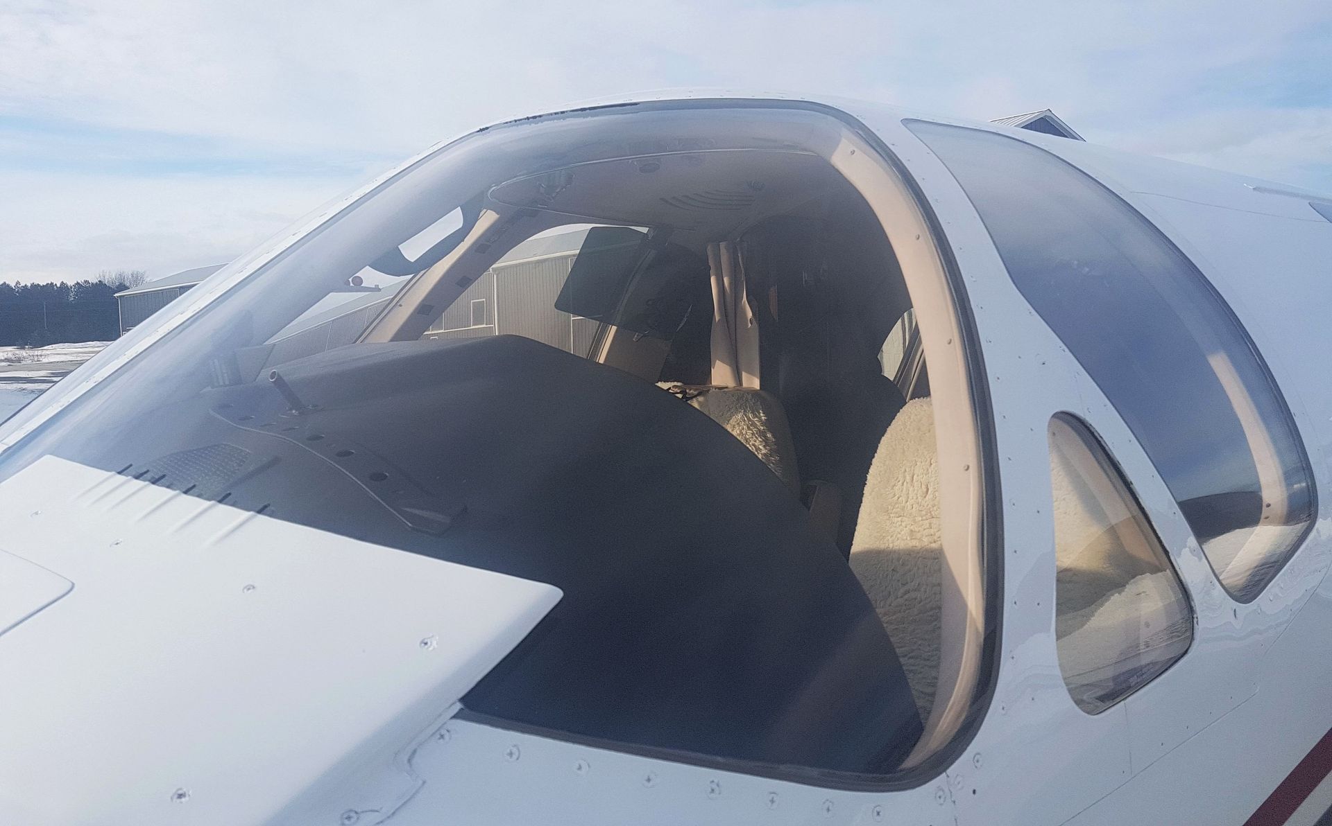 Close-up of a small white airplane cockpit with a transparent windshield.
