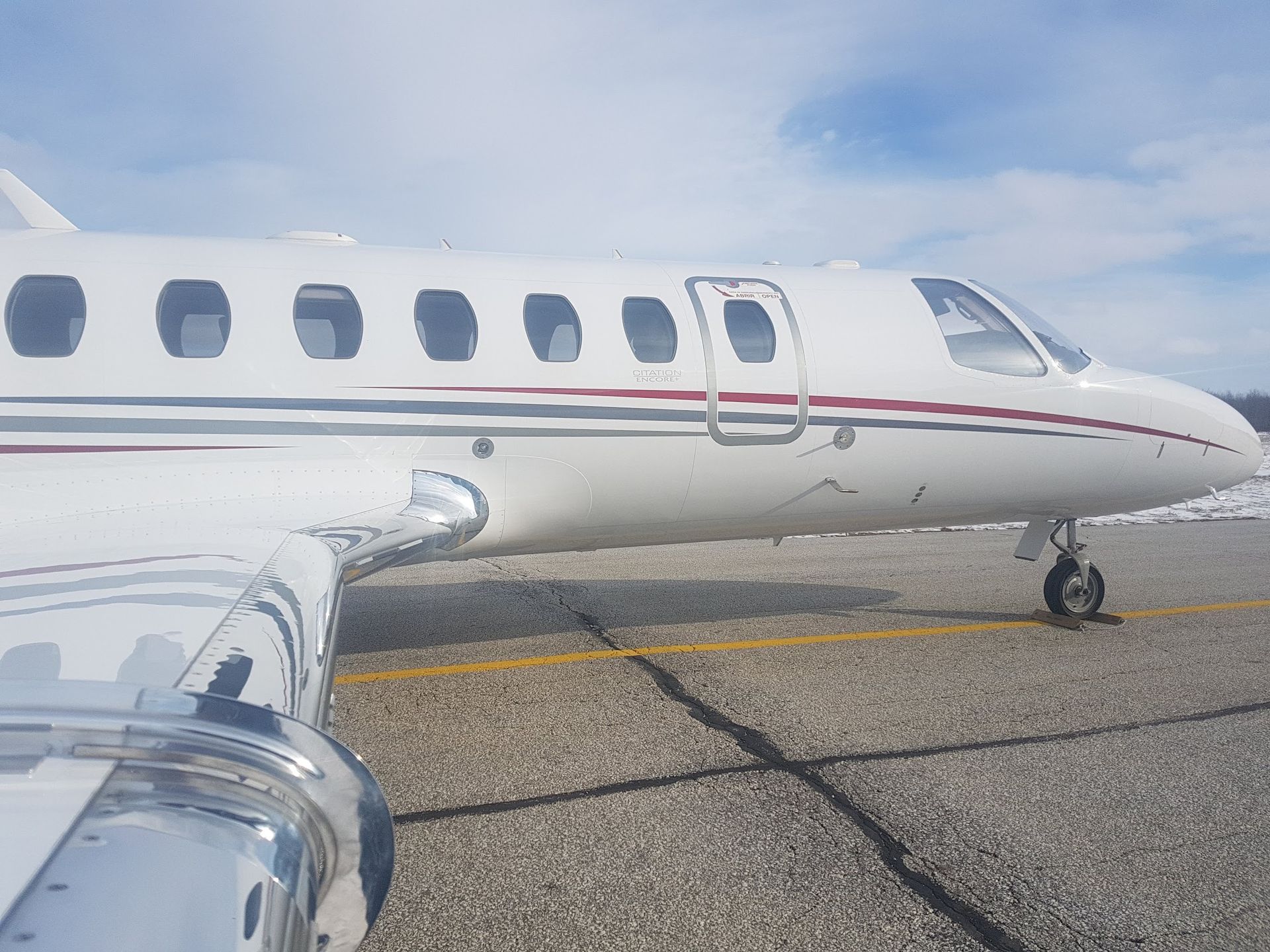 White private jet parked on a paved runway, under a partly cloudy sky.