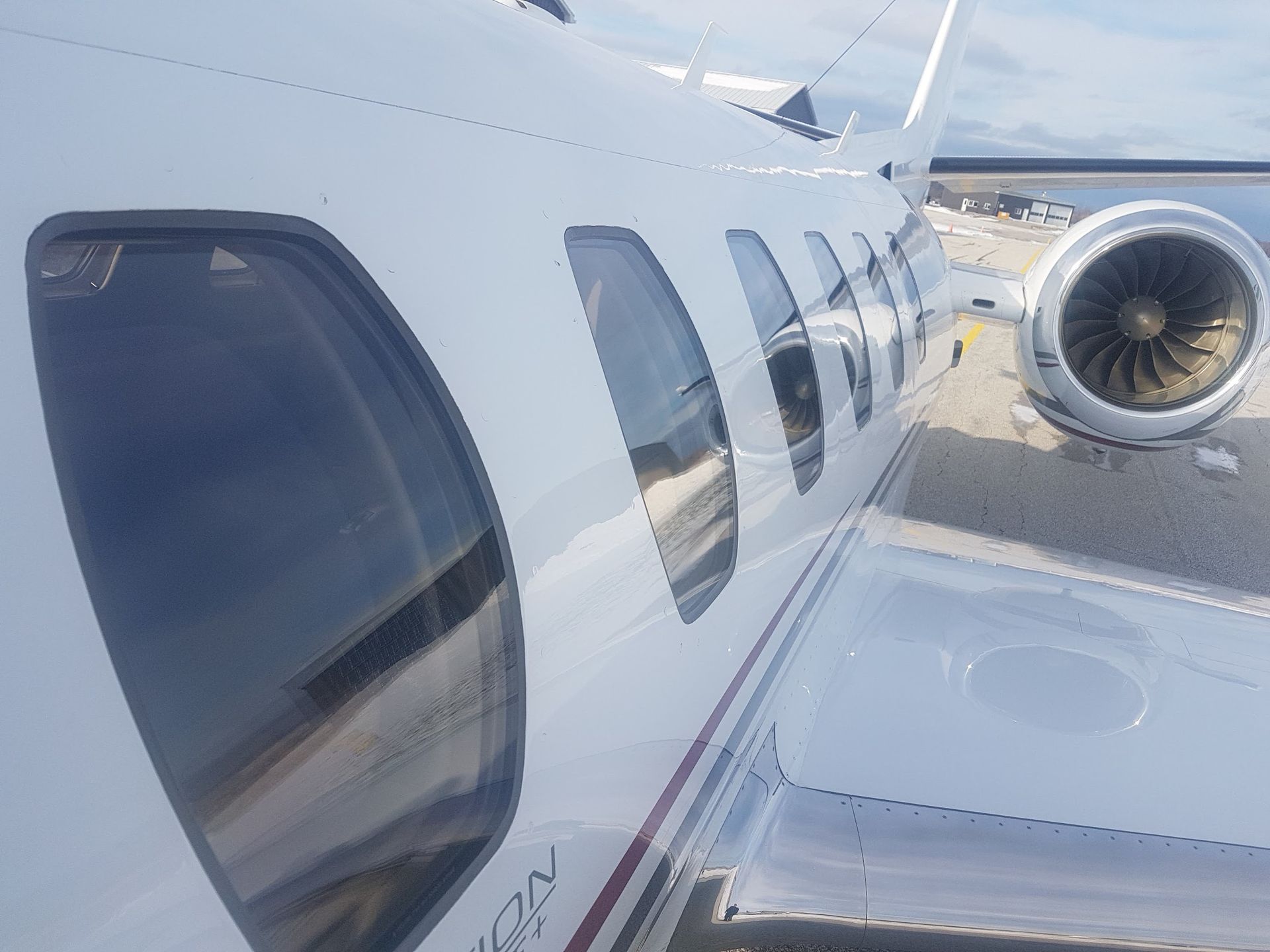 White airplane side with windows and jet engine.