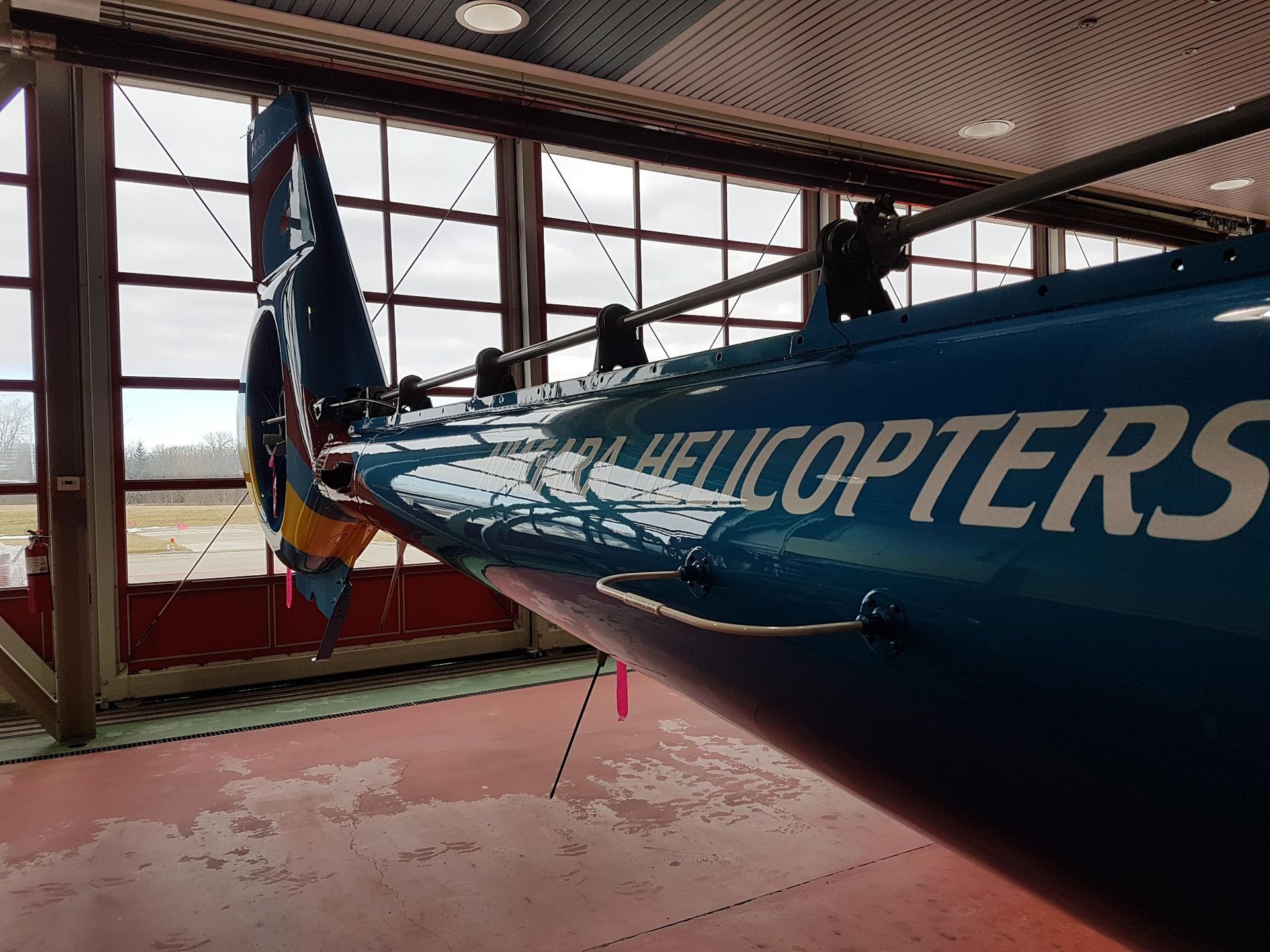 Blue helicopter tail section inside a hangar, with