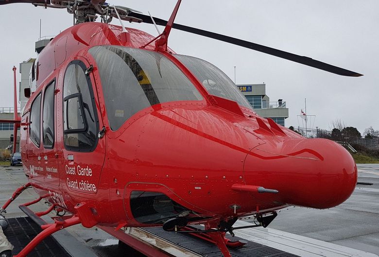 Red medical helicopter on a helipad, overcast sky.