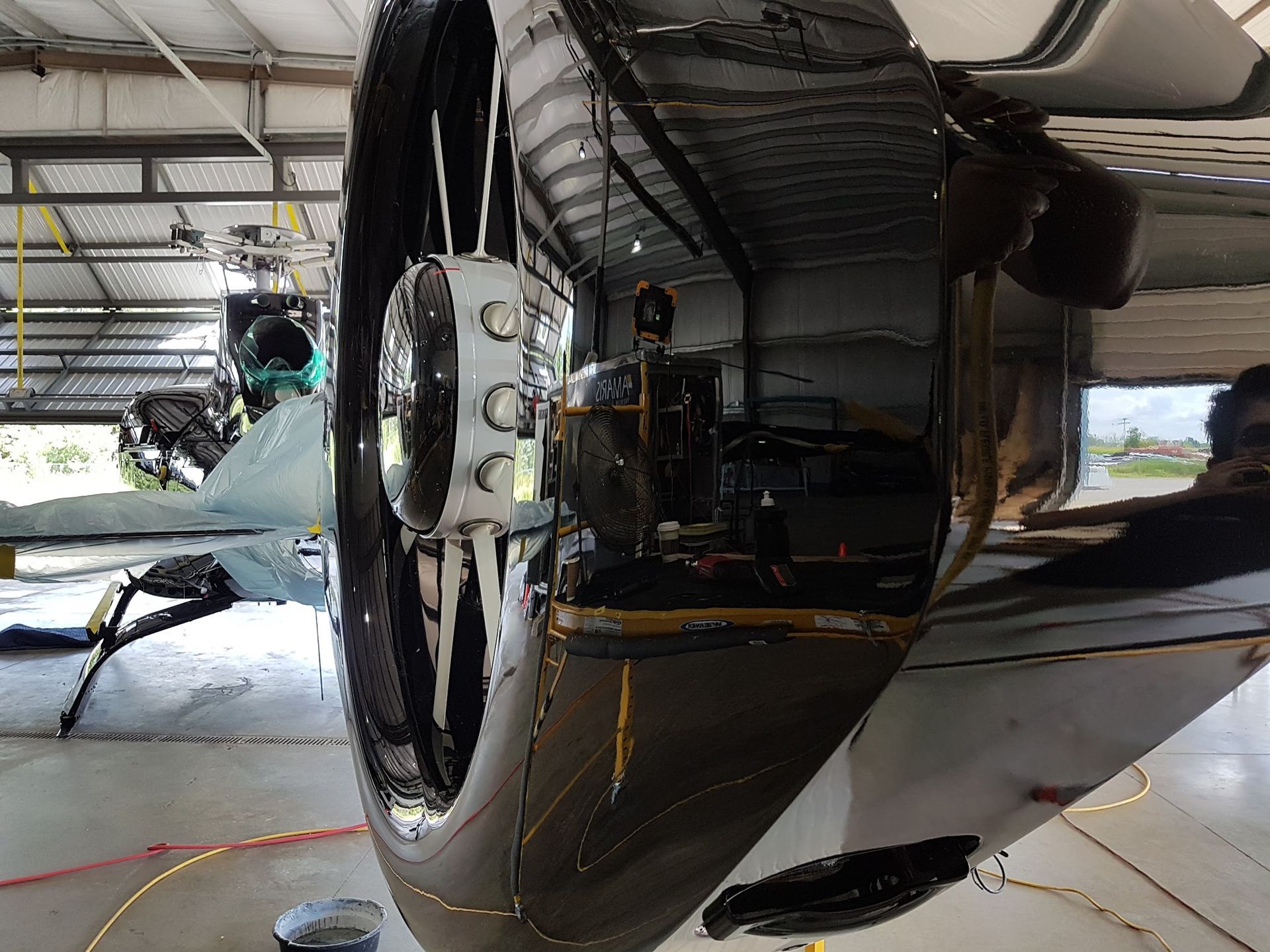 Black airplane engine in a hangar, reflective surface, with details of internal components.