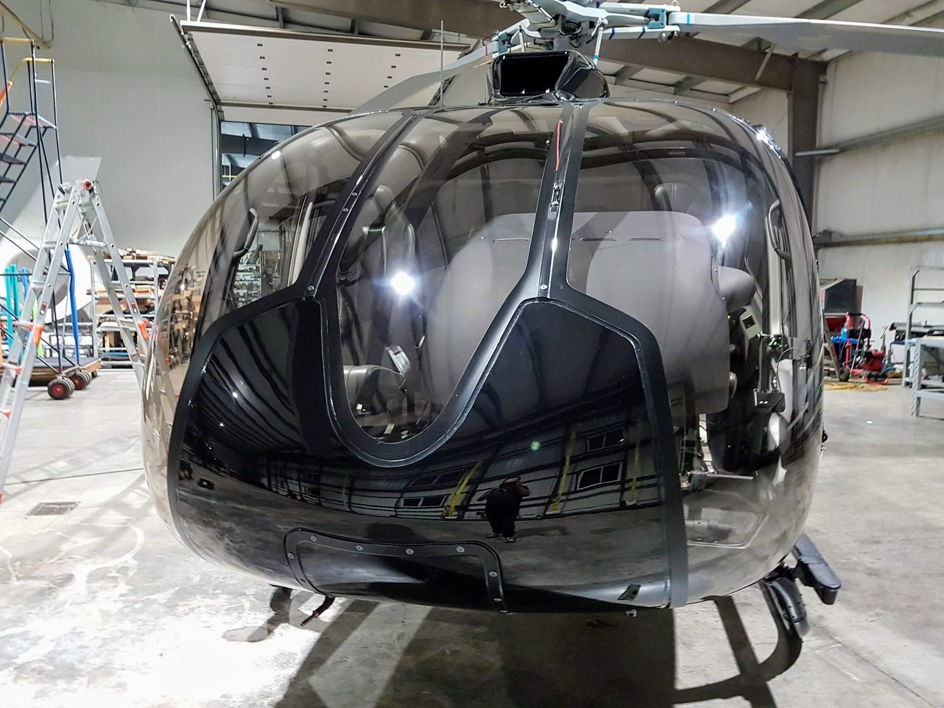Black helicopter with reflective glass canopy in a hangar.