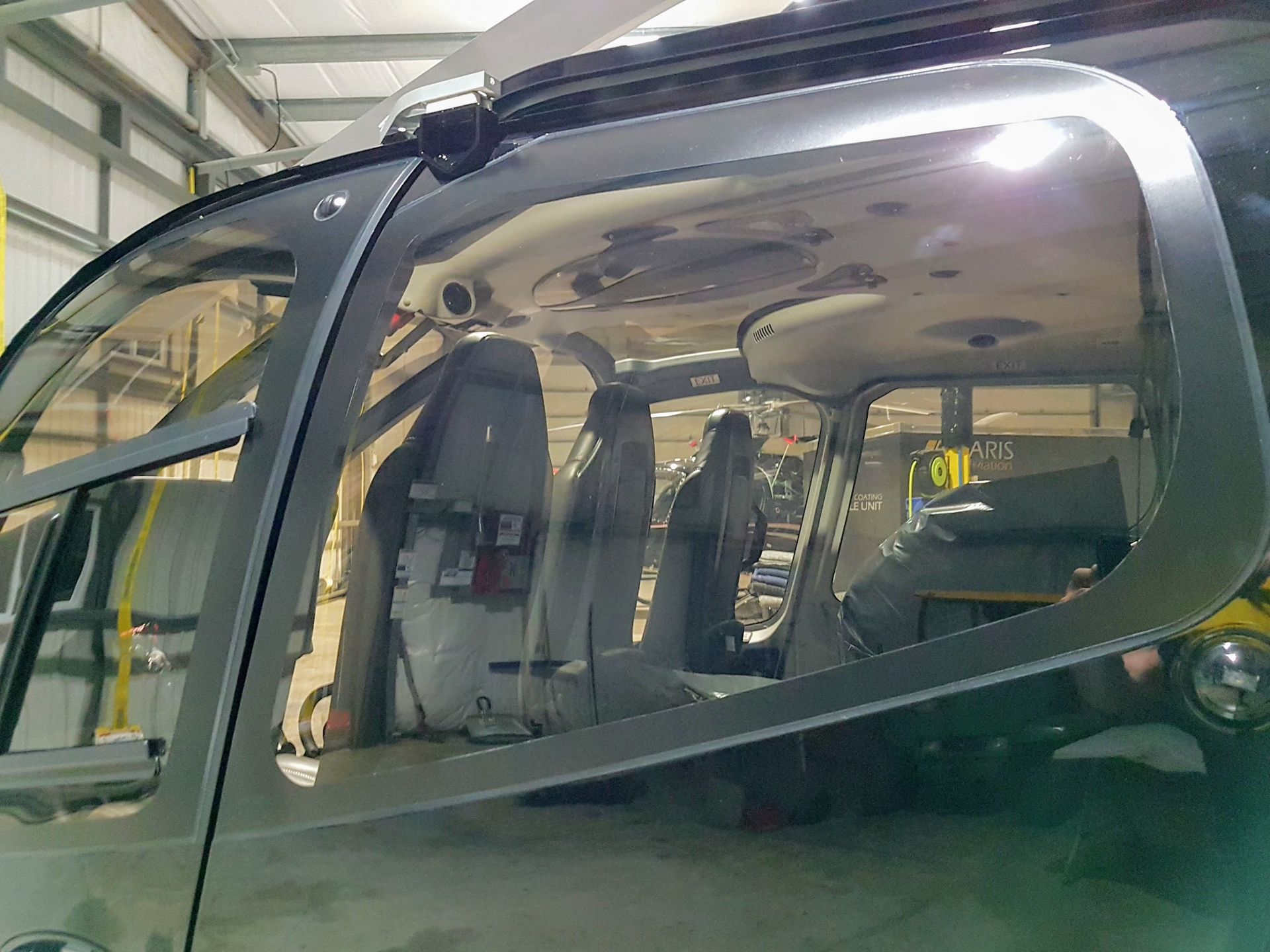 Side view of helicopter interior with seats visible through the windows, gray frame.