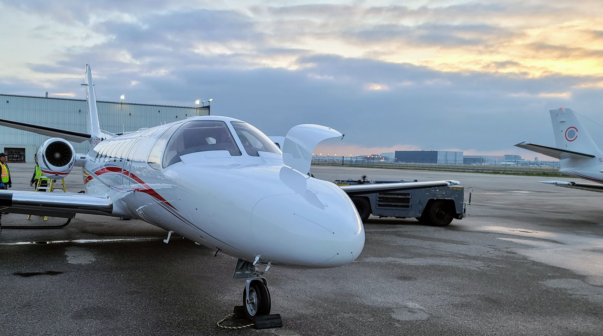 White private jet on tarmac; overcast sky.