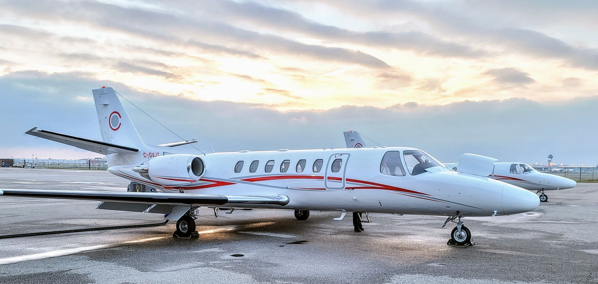Two white airplanes on a tarmac under a cloudy sky.