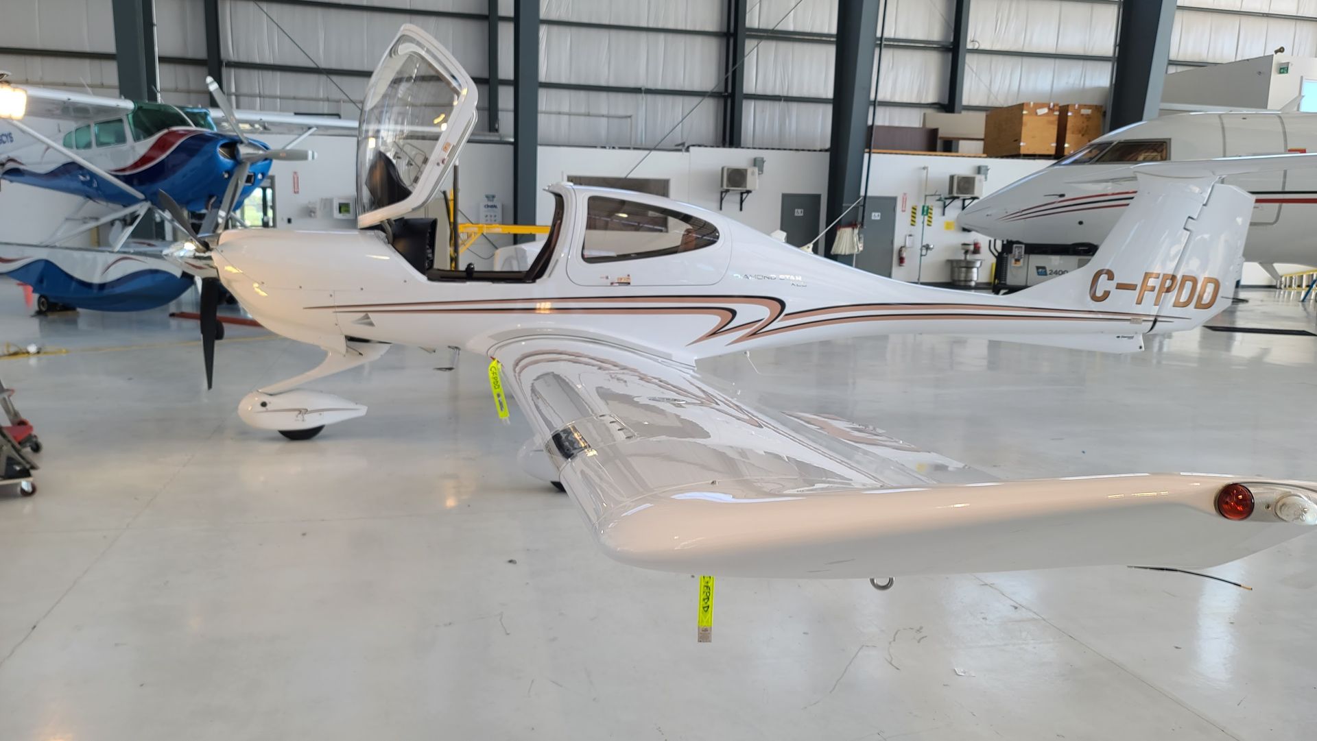 White airplane with open door in a hangar. Brown trim, yellow safety flags.