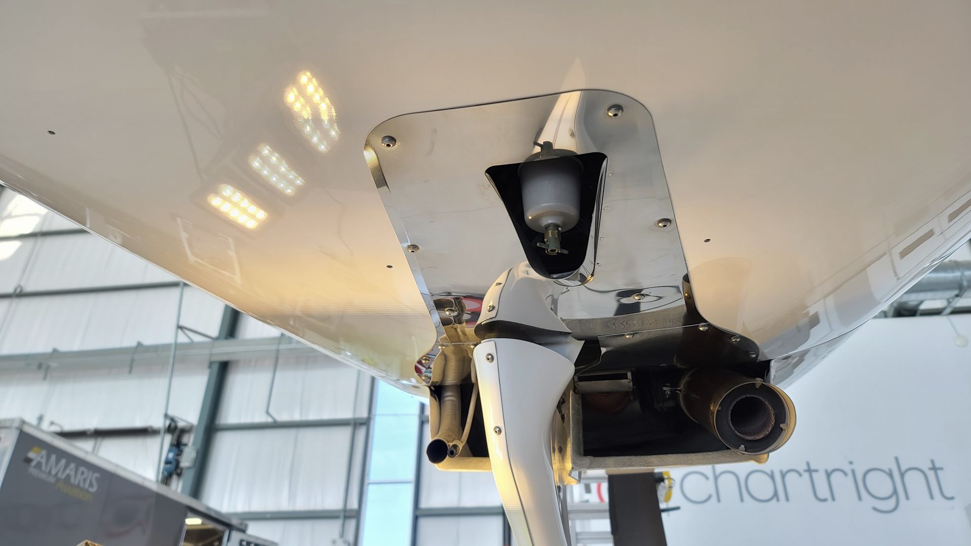 Underside view of a white aircraft fuselage, showing the tail wheel assembly.