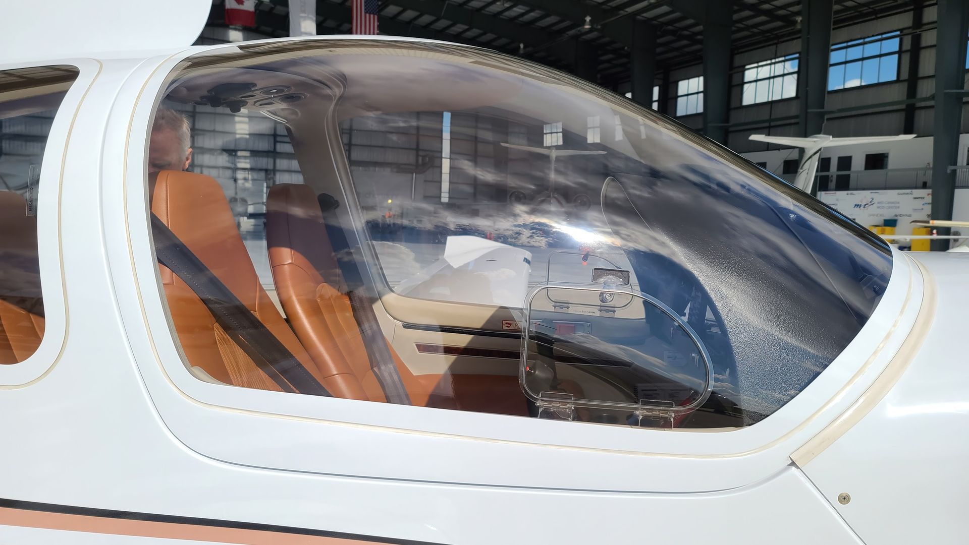 Close-up of a small plane's cockpit with brown seats visible through the clear canopy.
