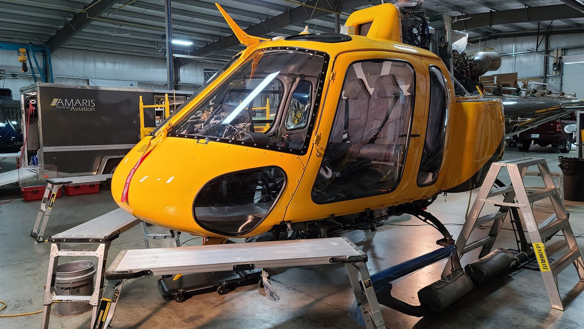 Yellow helicopter fuselage in a repair shop.