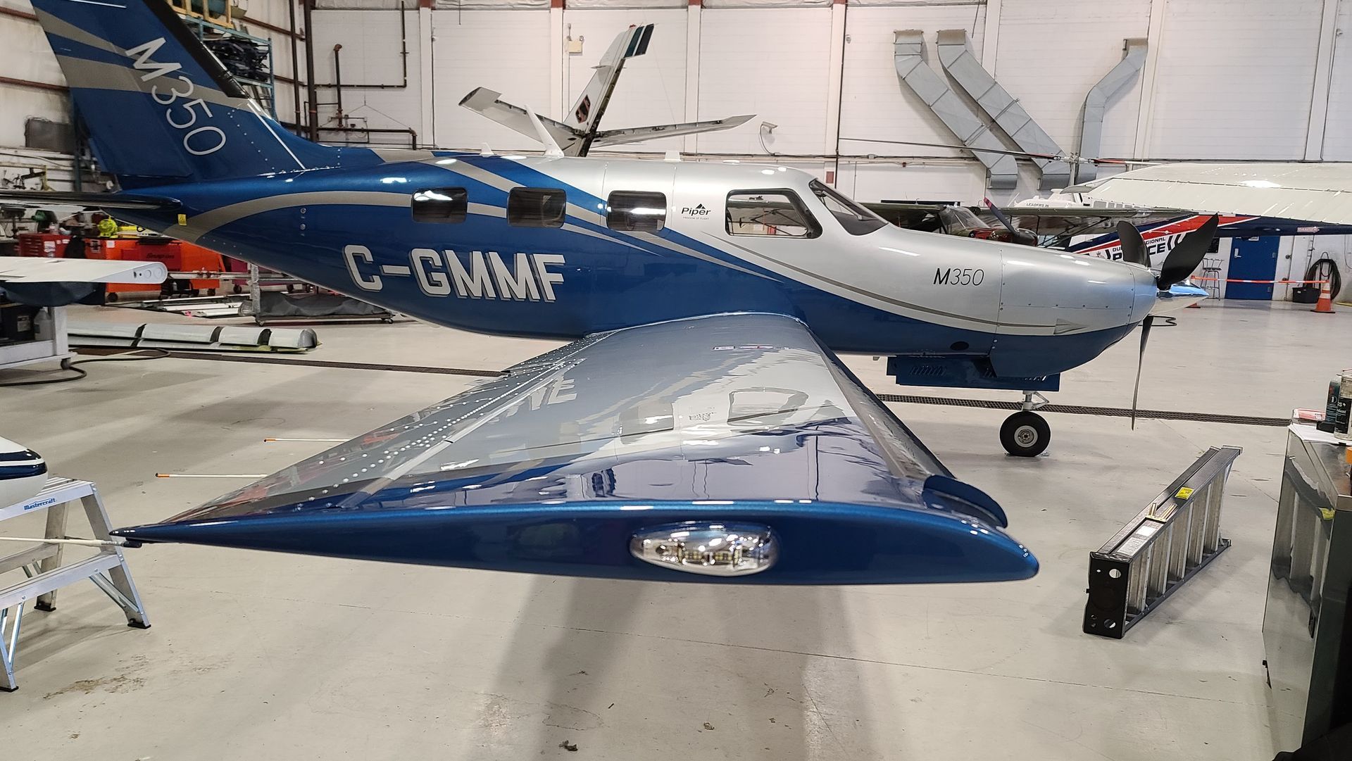 Blue and silver Cessna M750 airplane inside a hangar, wings visible.
