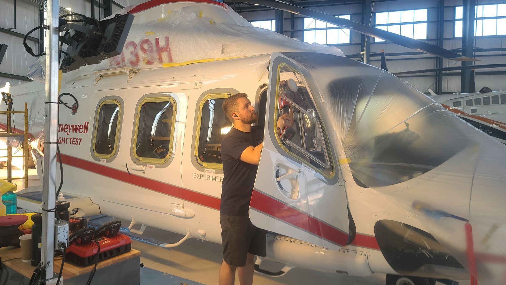 Person working on a white and red helicopter in a hangar.