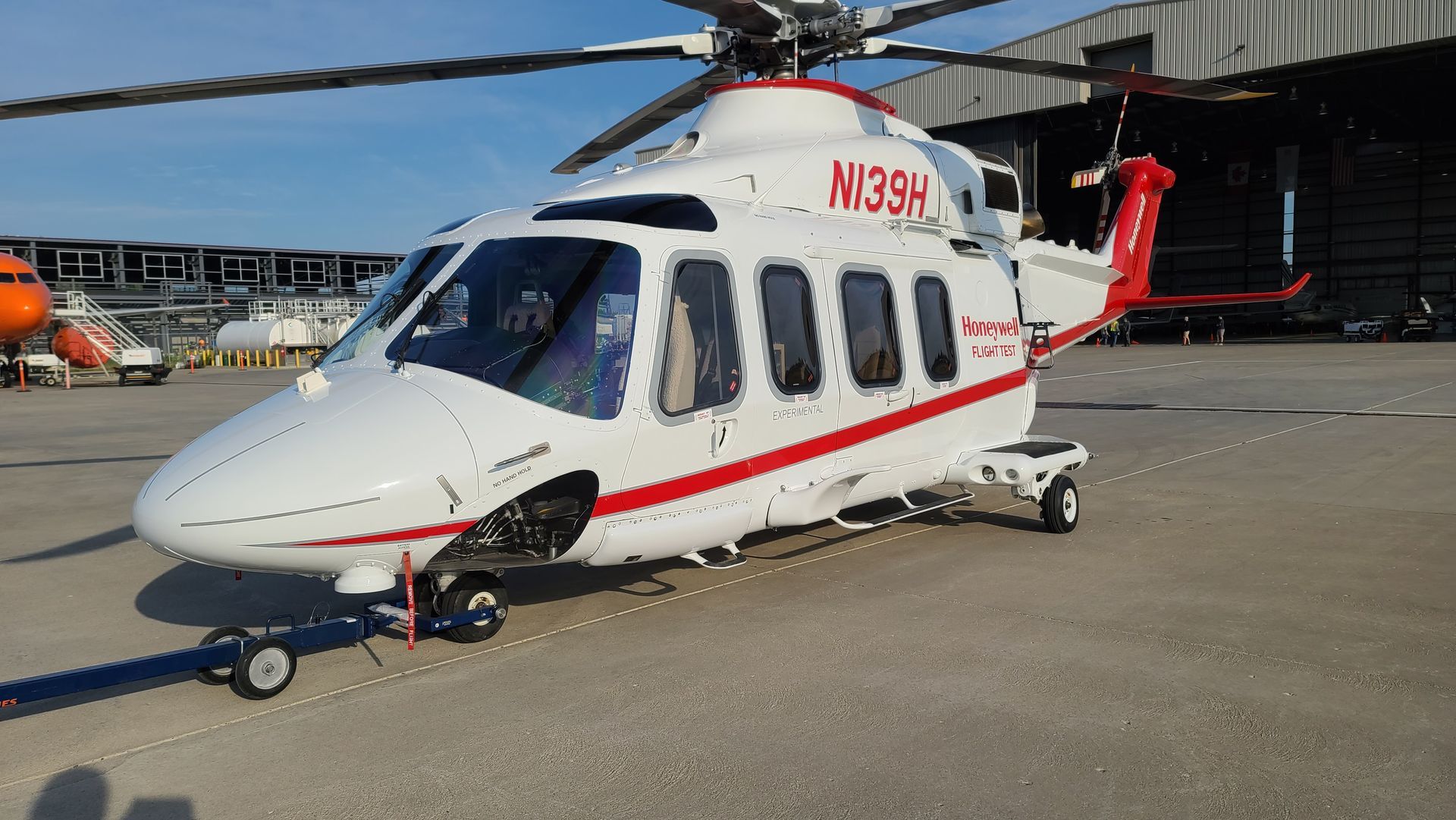 White and red helicopter on a tarmac, registration N133H, with a blue sky background.
