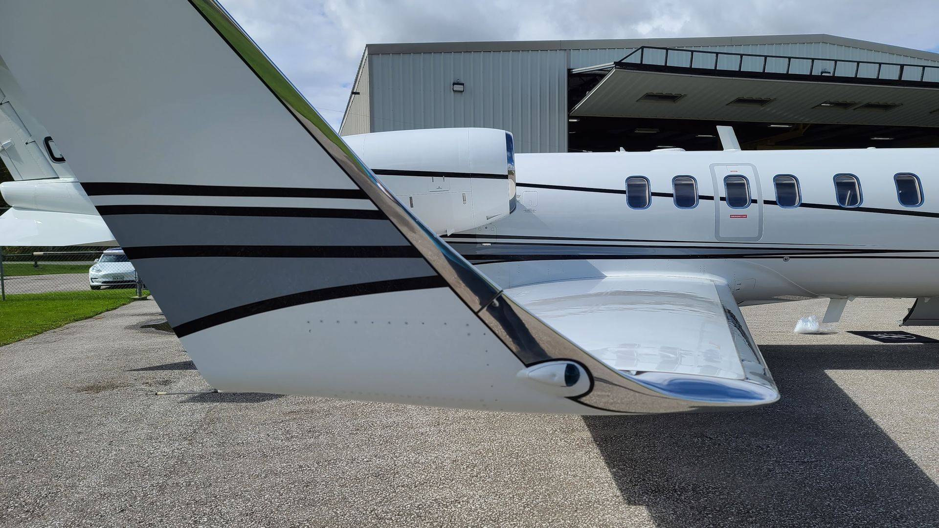 Tail of white and grey jet airplane parked near a hangar.