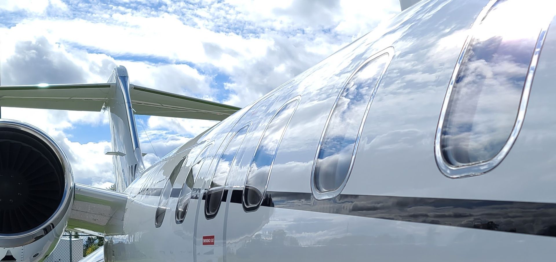 Close-up of a jet plane wing with clear winglets, reflecting the sky and clouds.