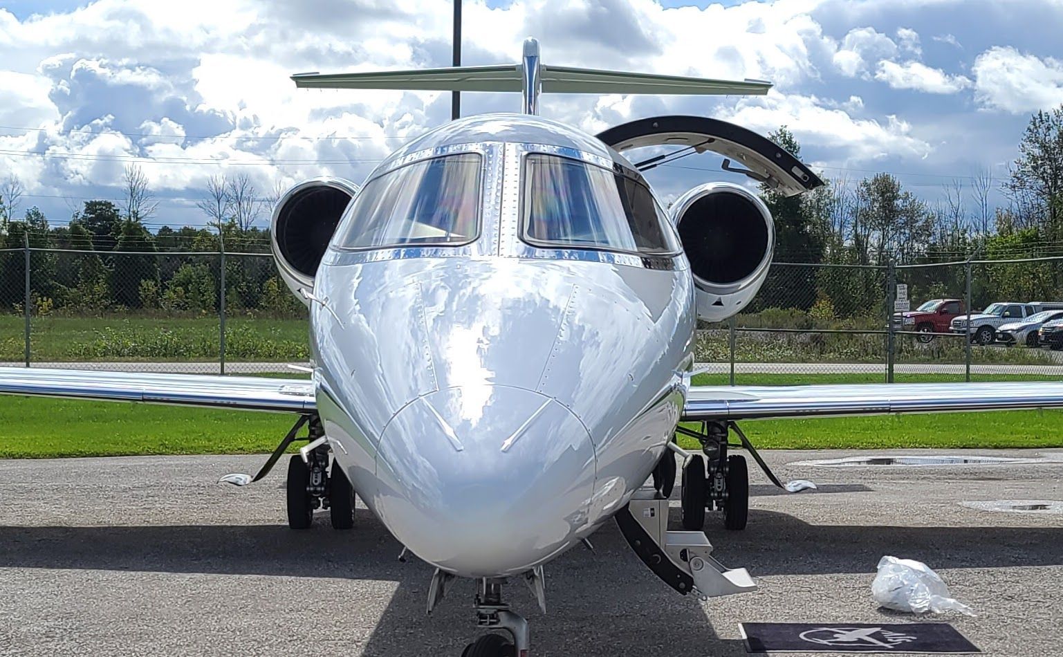 White private jet parked on tarmac with open door, front view.