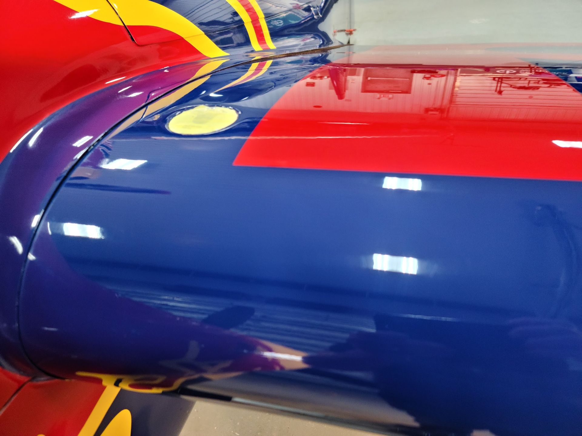 Close-up of a brightly colored aircraft wing in blue, red, and yellow.