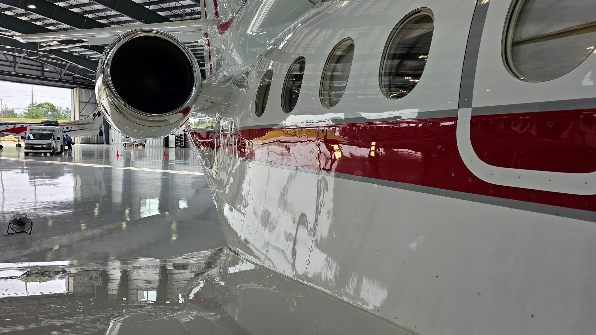White and red airplane in a hangar, reflecting on the glossy floor.