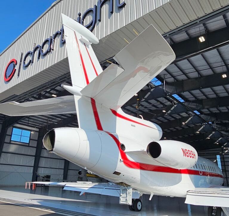 White and red private jet inside a hangar labeled