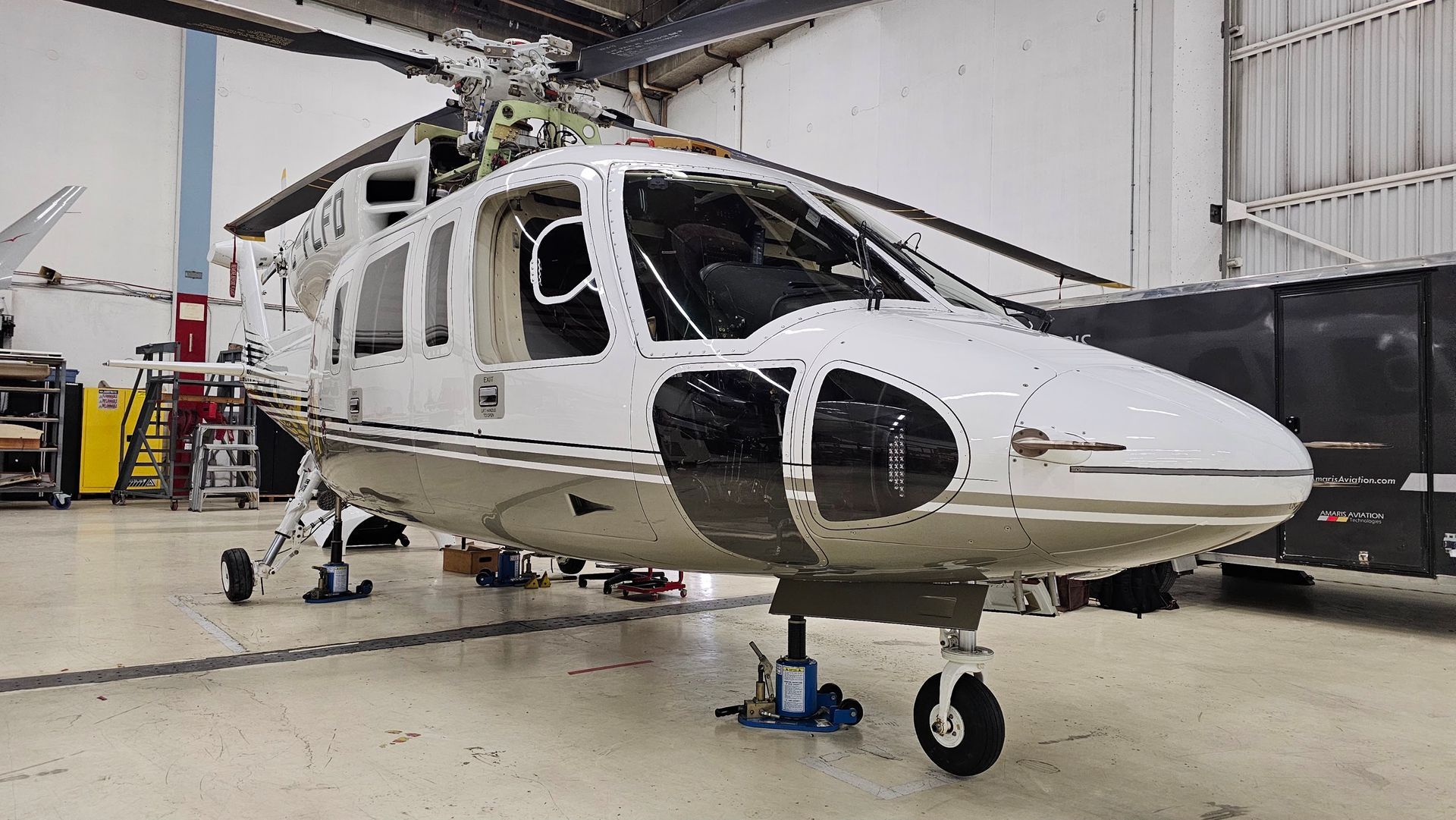 White helicopter in a hangar, parked on jacks.
