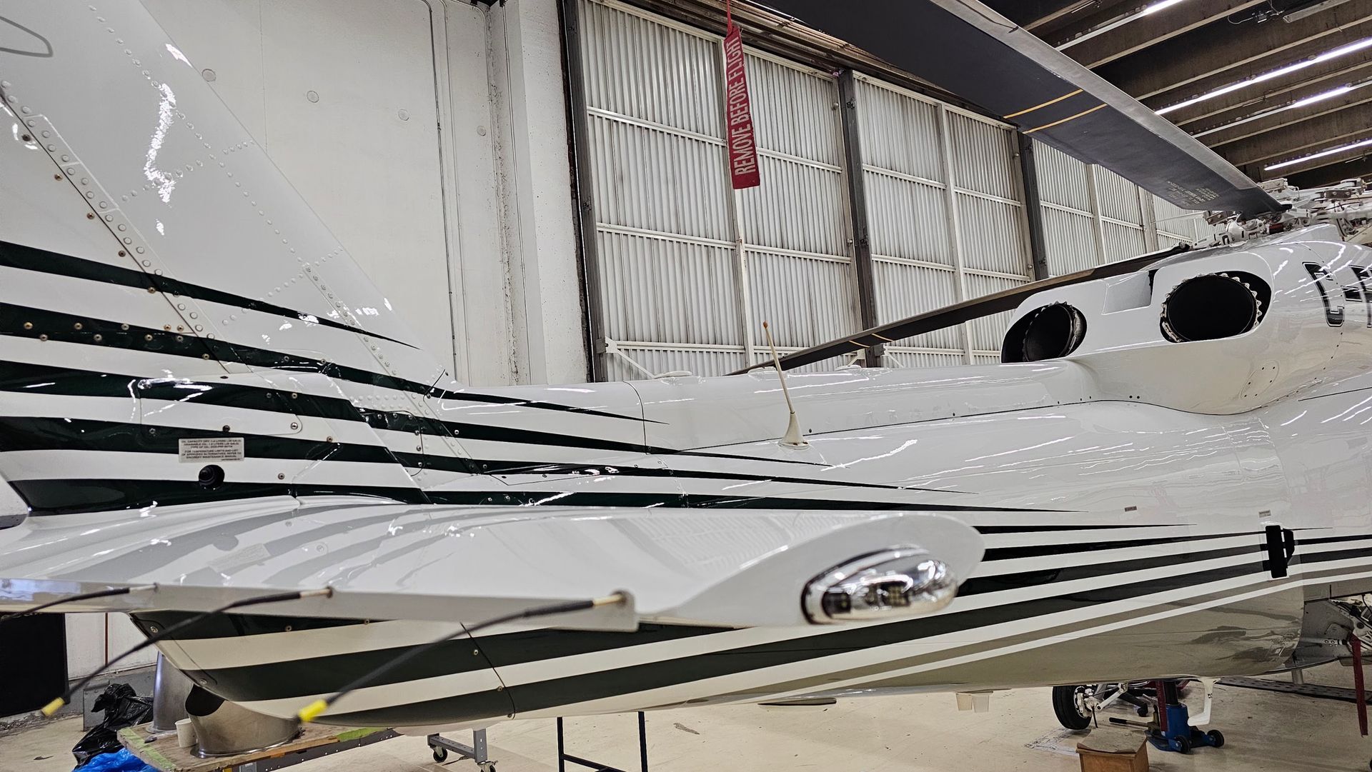 White airplane wing with dark green stripes in a hangar.