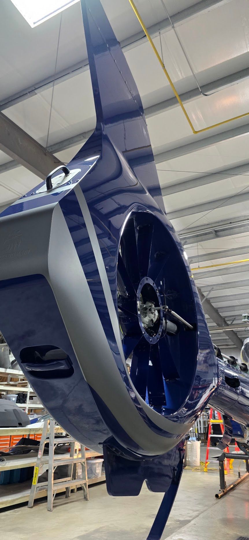 Blue and silver aircraft component with an internal fan, indoors.