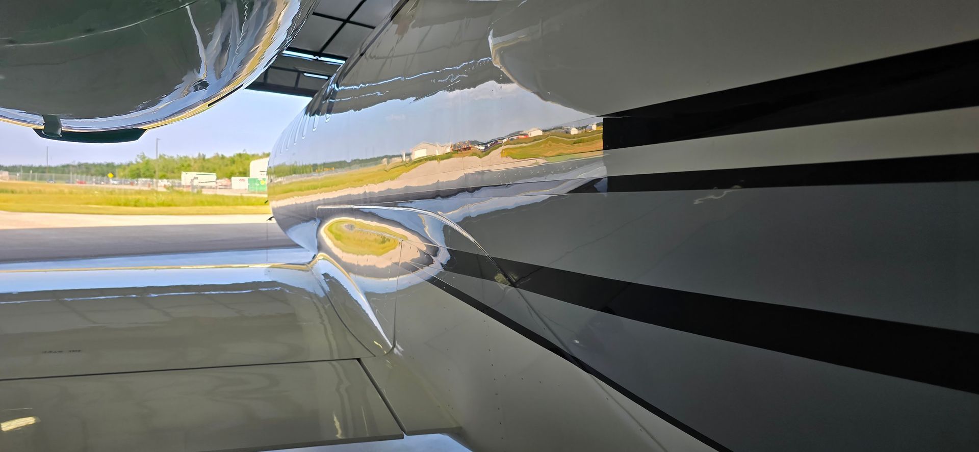 View of an aircraft wing, focusing on the engine cowling and a propeller against a runway background.