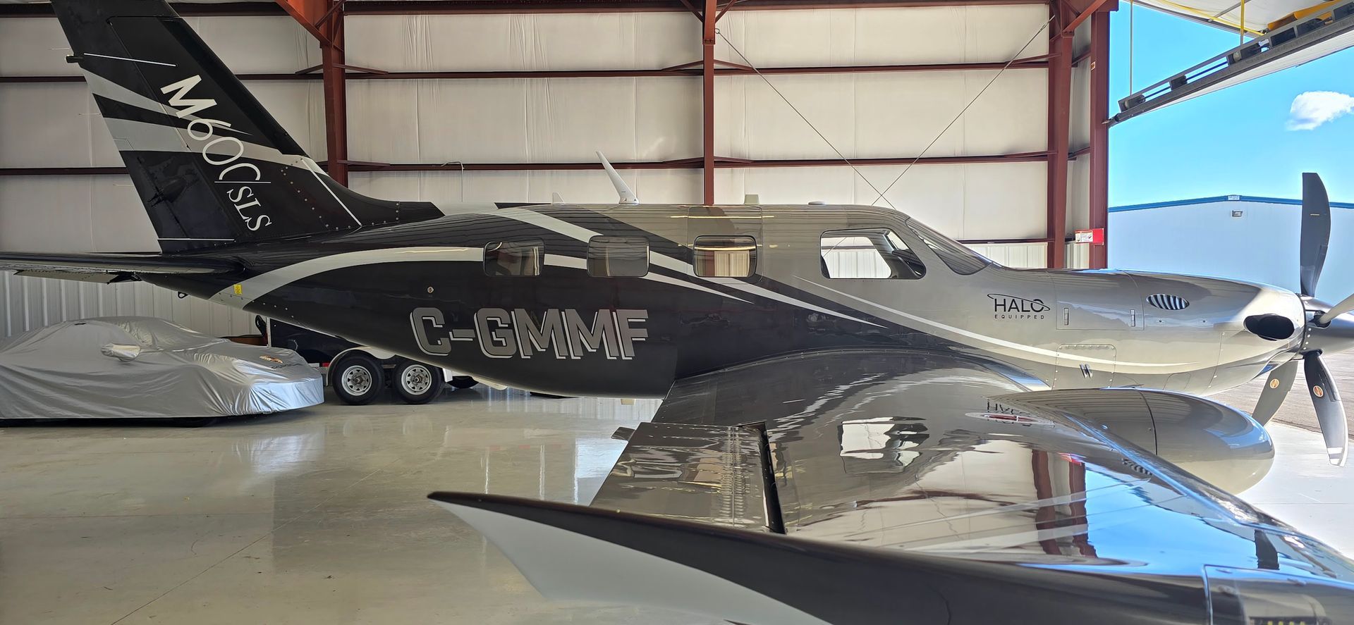 A silver and black airplane inside a hangar with a white and black tail.