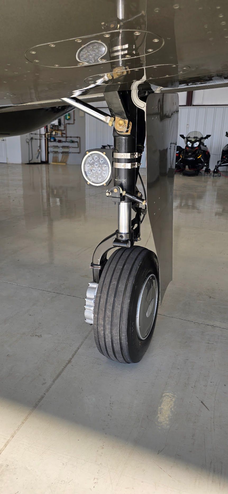 Aircraft landing gear with tire on a concrete surface. A light is attached.