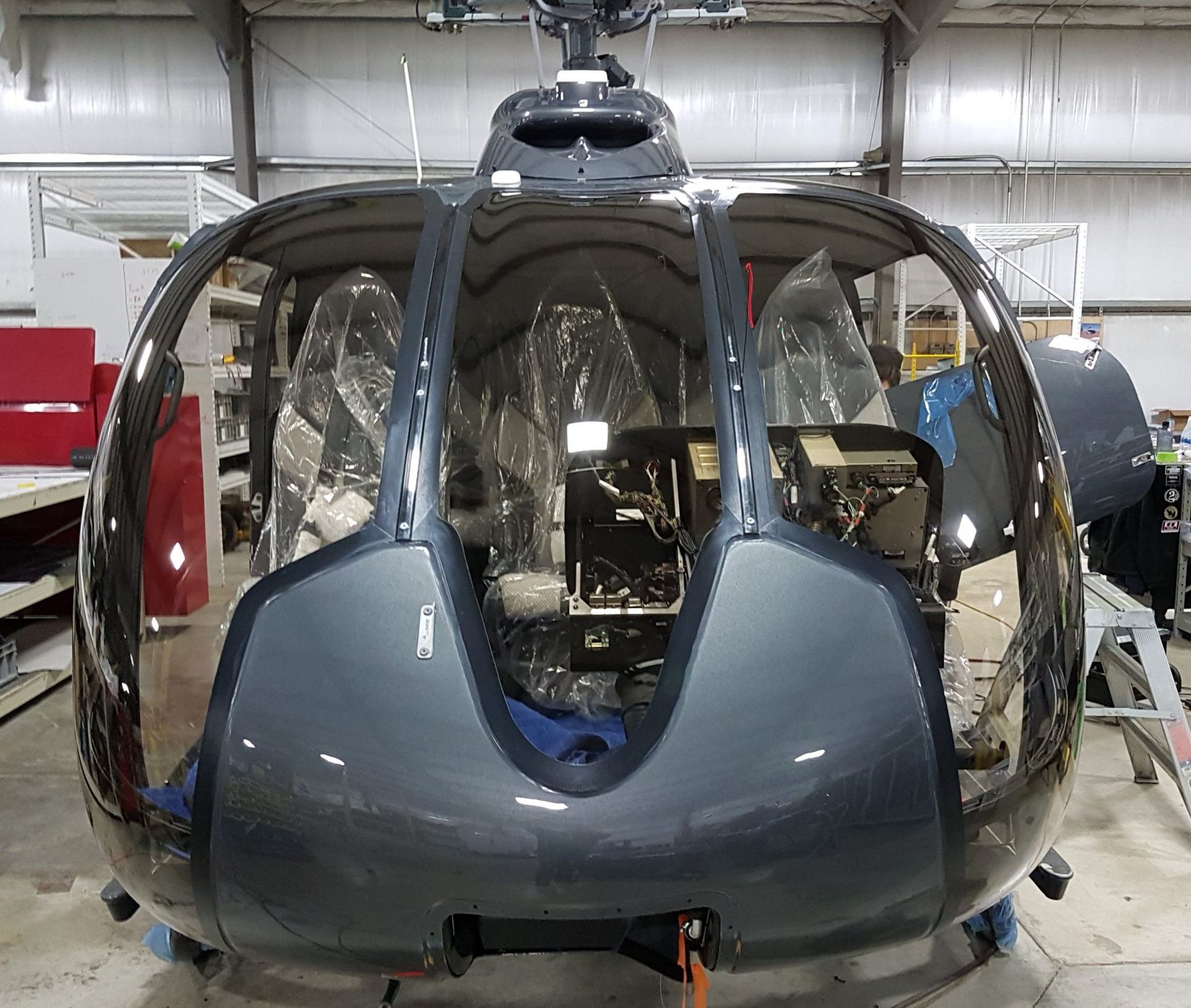 Dark gray helicopter fuselage in a workshop.