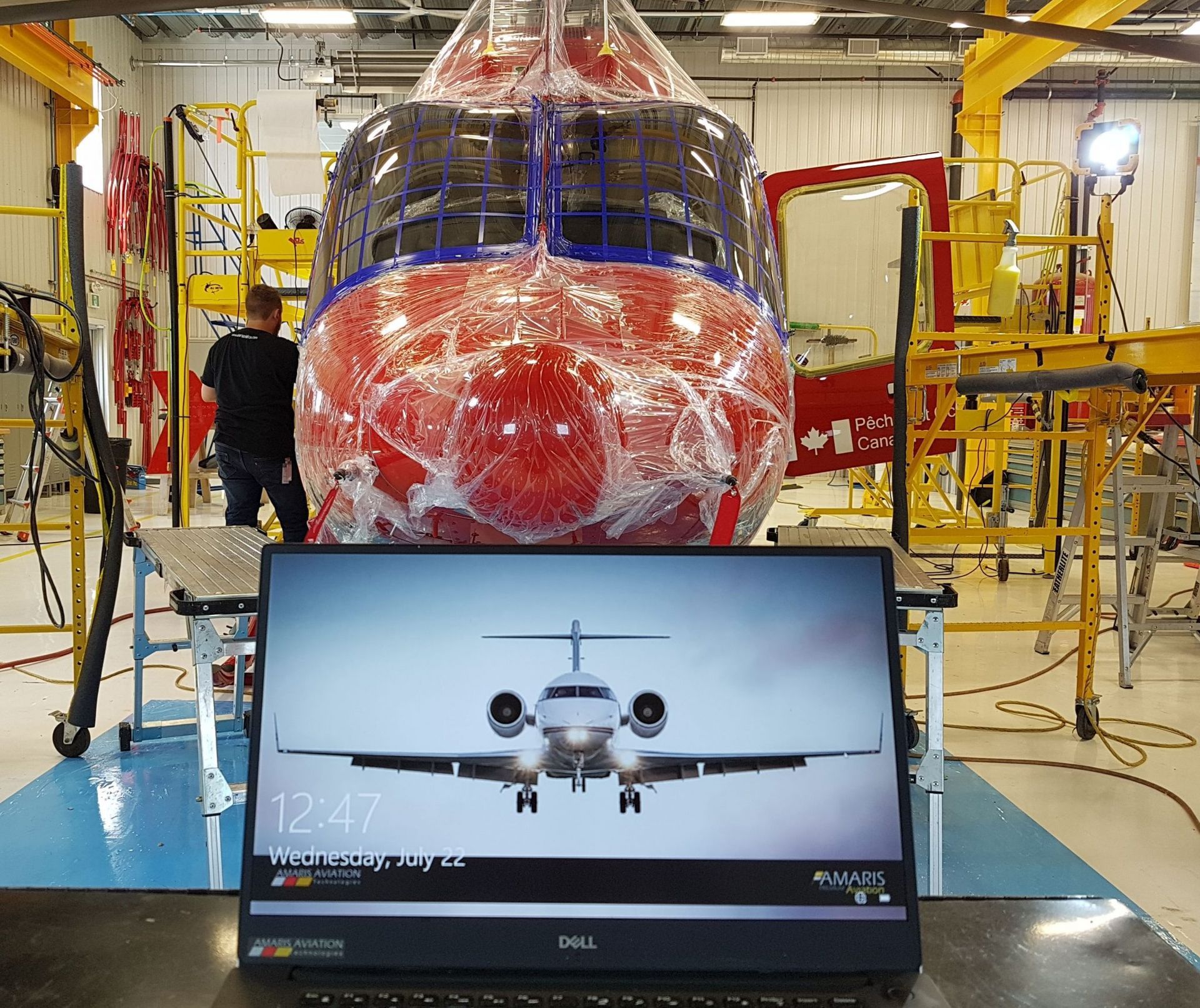 Computer screen with airplane image in front of a red aircraft fuselage in a hangar.