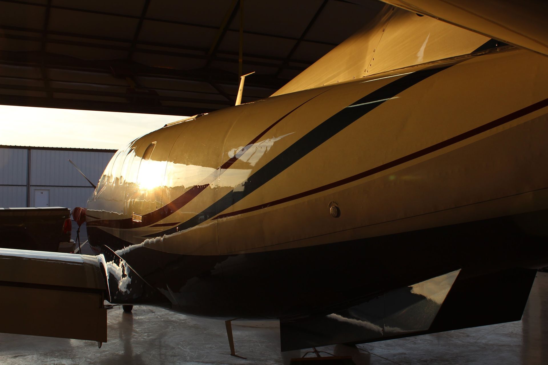 Yellow and black airplane side in a hangar, reflecting sunlight.