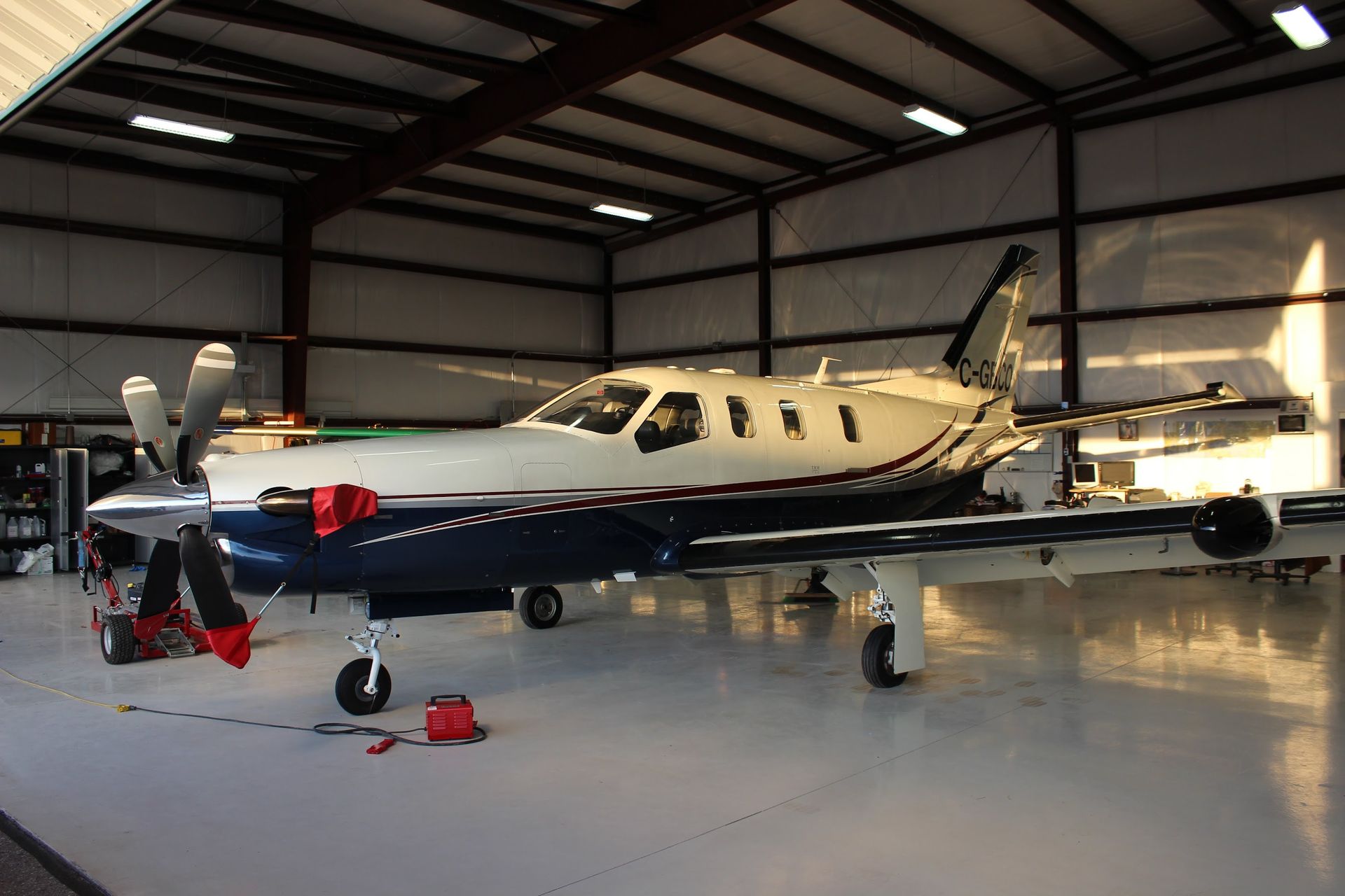 Airplane parked inside a hangar; blue, white, and silver fuselage; two propellers.