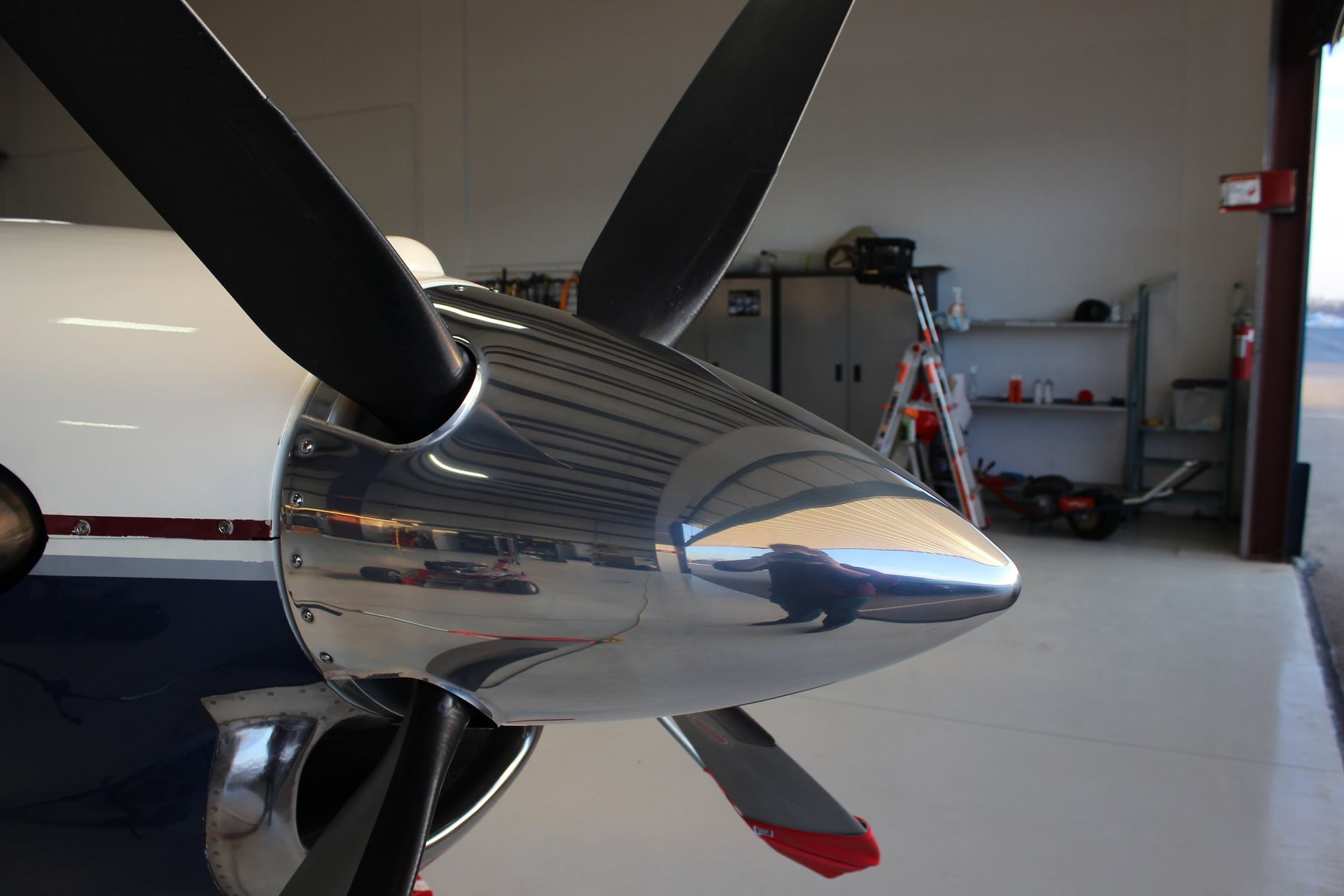 Shiny propeller of an airplane parked in a hangar. Black blades, reflective metal.